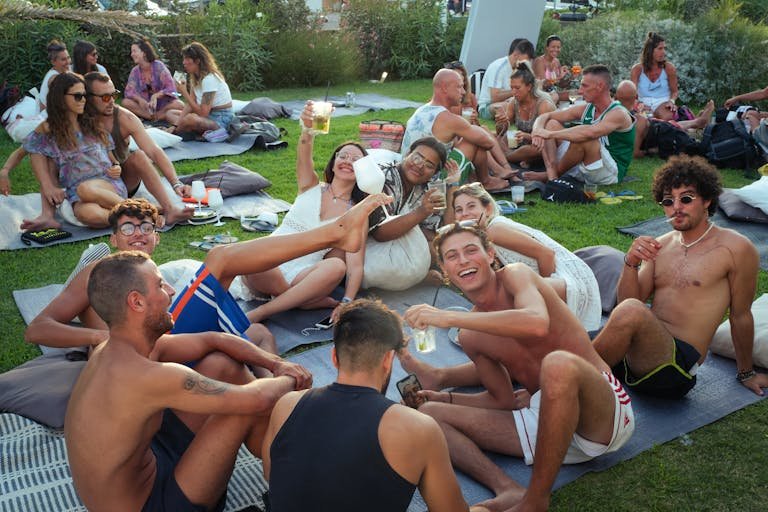 Group enjoying an outdoor summer party in Cervia, Italy, with laughter and drinks.